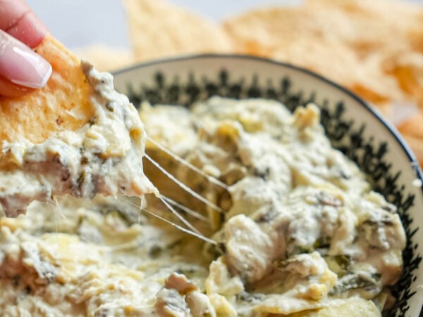 photo of a tortilla chip scooping Crockpot Spinach and Artichoke Dip