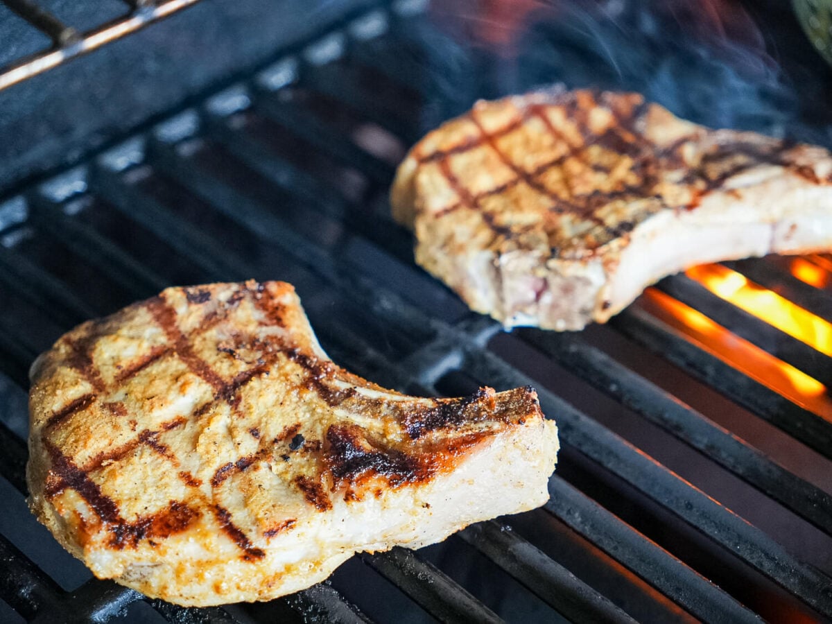 photo of grilled pork chops on a grill with fire in the background