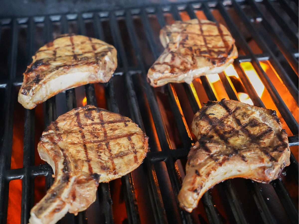 photo of pork chops cooking on a grill with fire in the background