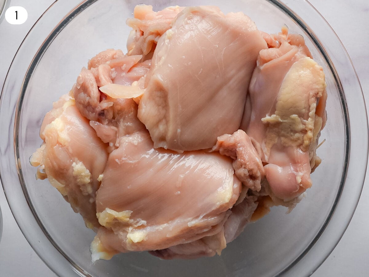 step 1 photo of cleaned dry chicken thighs in a glass bowl