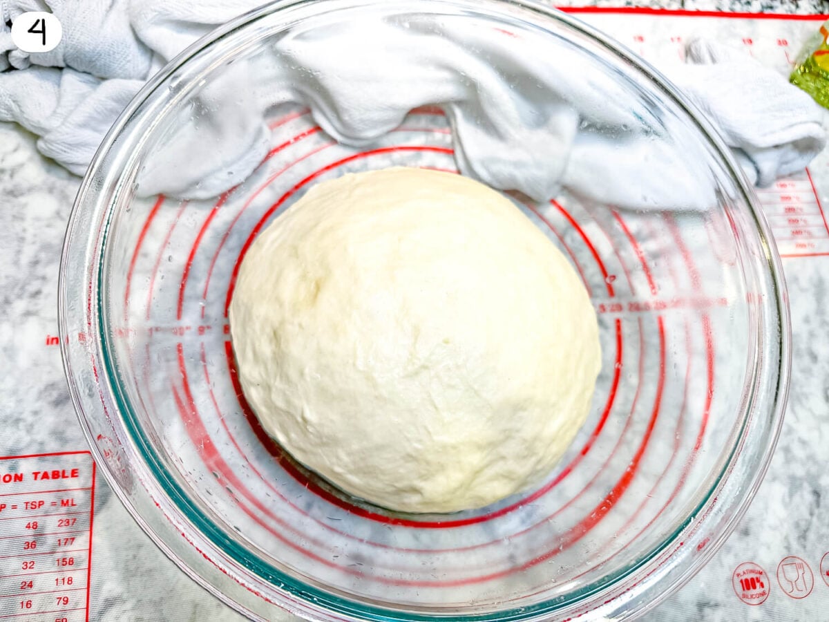 step 4 photo of pizza dough proofing in a glass bowl