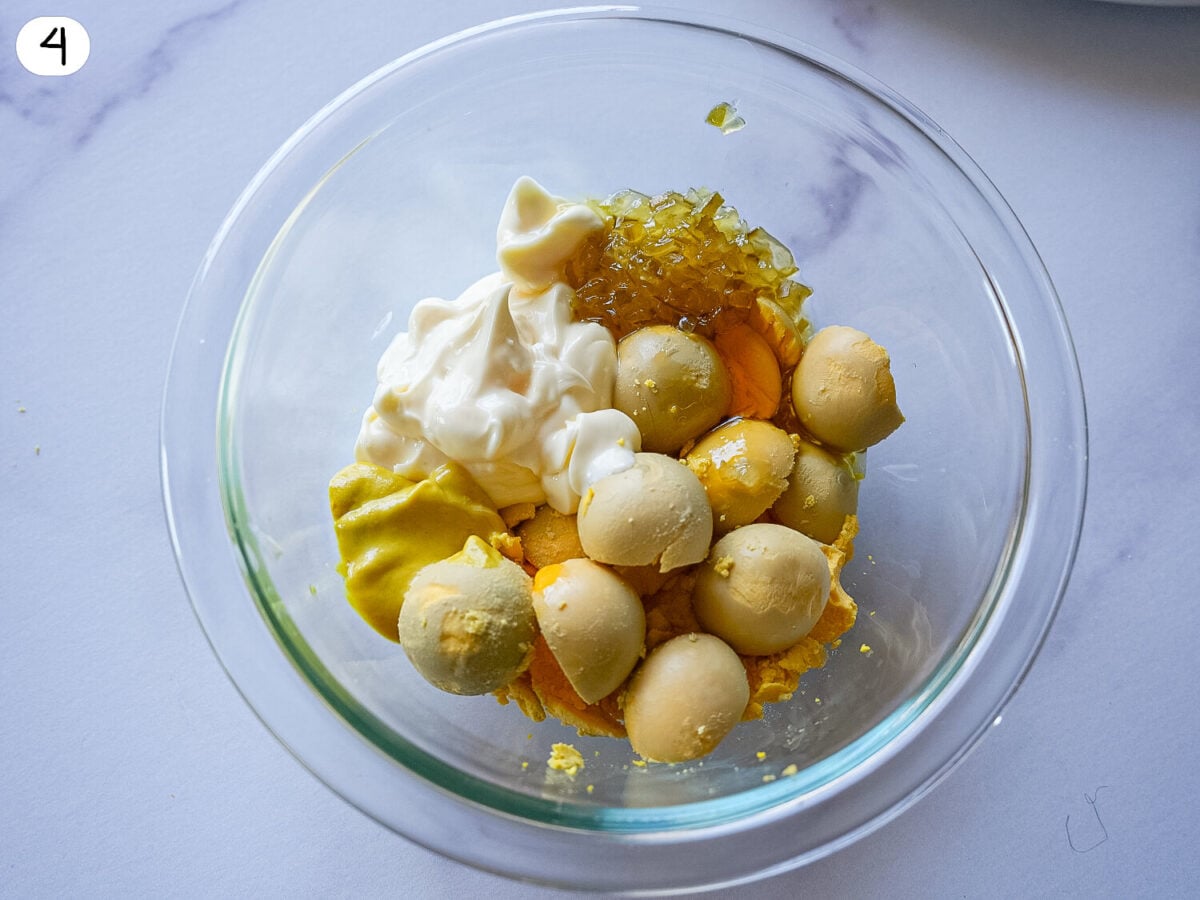step 4 photo showing egg yolks removed and in a glass bowl with other ingredients