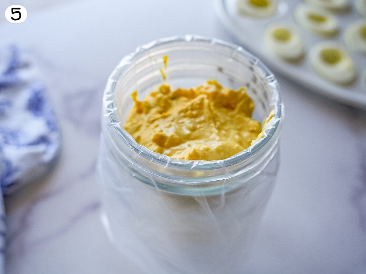 step 5 photo of Deviled Eggs filling inside of a piping bag that's inside a jar