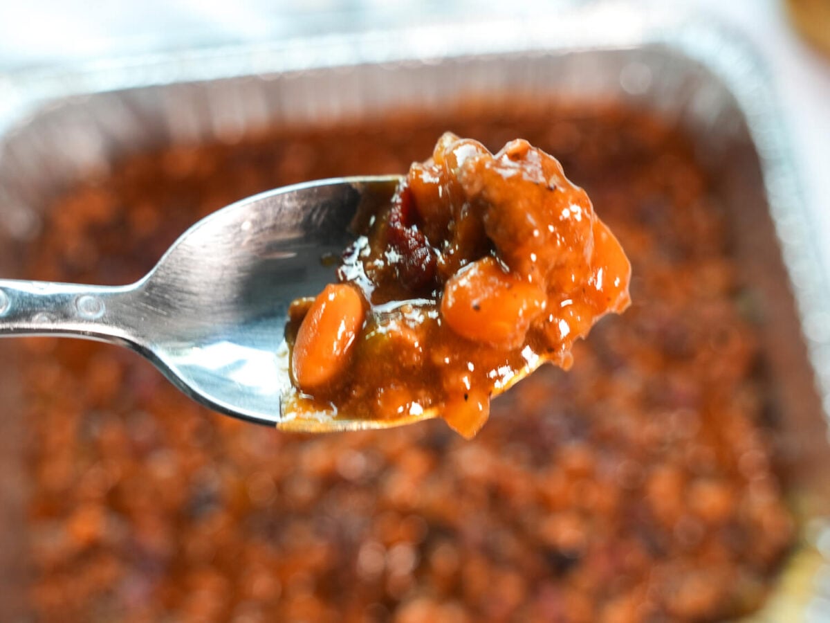 close up photo of a small spoon full of southern bbq baked beans