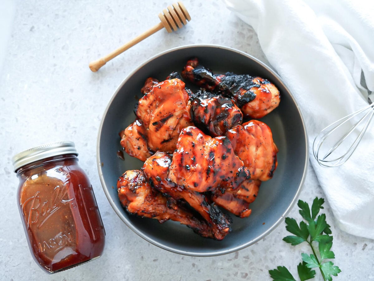 overhead photo of honey bbq chicken next to a jar of homemade honey bbq sauce