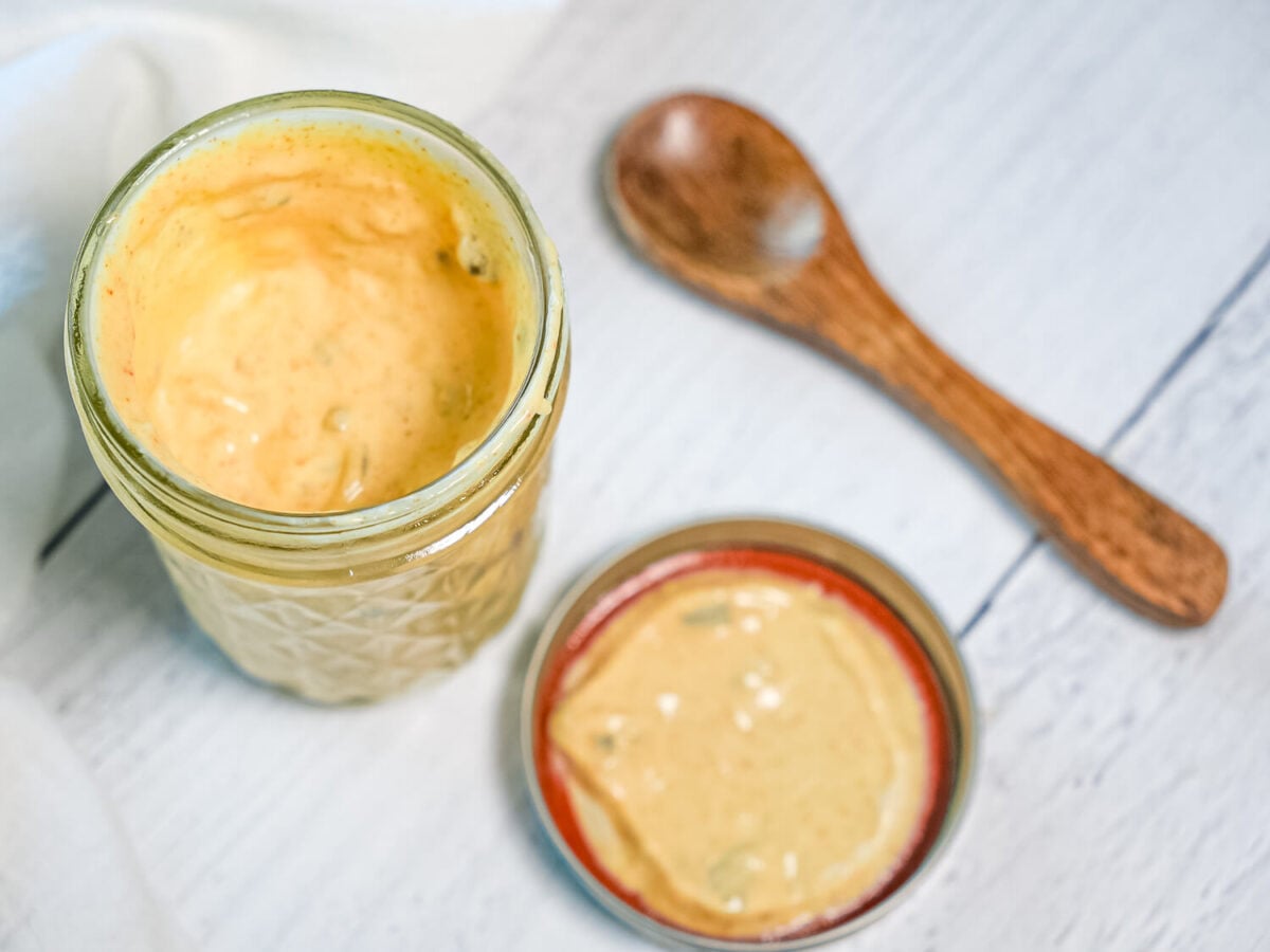 photo of Copycat Big Mac Sauce in a mason jar next to a lid and wooden spoon