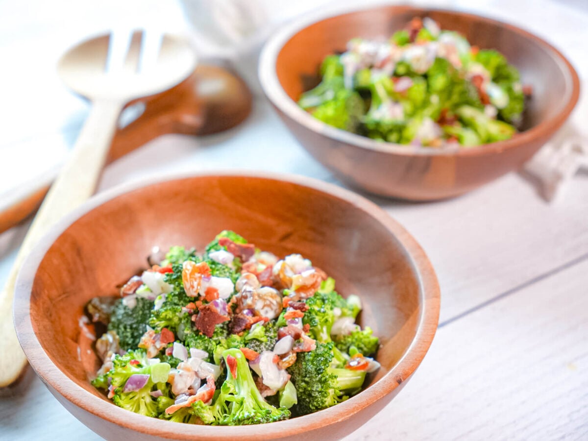 photo showing two bowls of broccoli salad with bacon in wooden bowls