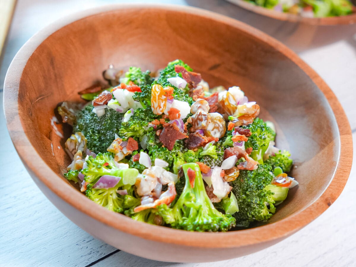 side view photo of broccoli salad with bacon and dressing in a wooden bowl