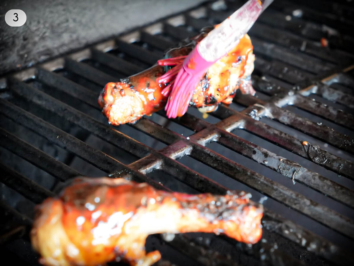 step 3 photo of chicken being sauced on the grill