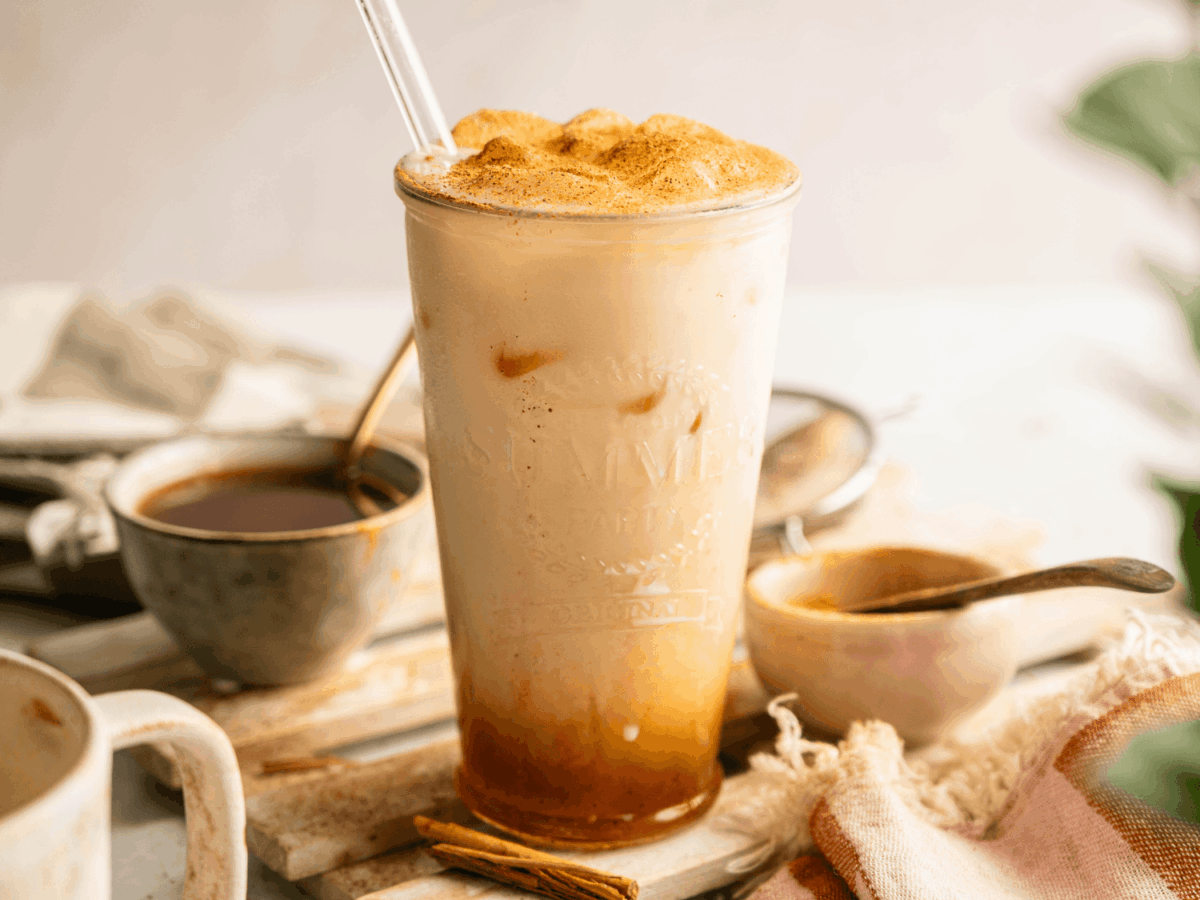 Front shot photo of a Iced Pumpkin Cream Chai with syrup in the background