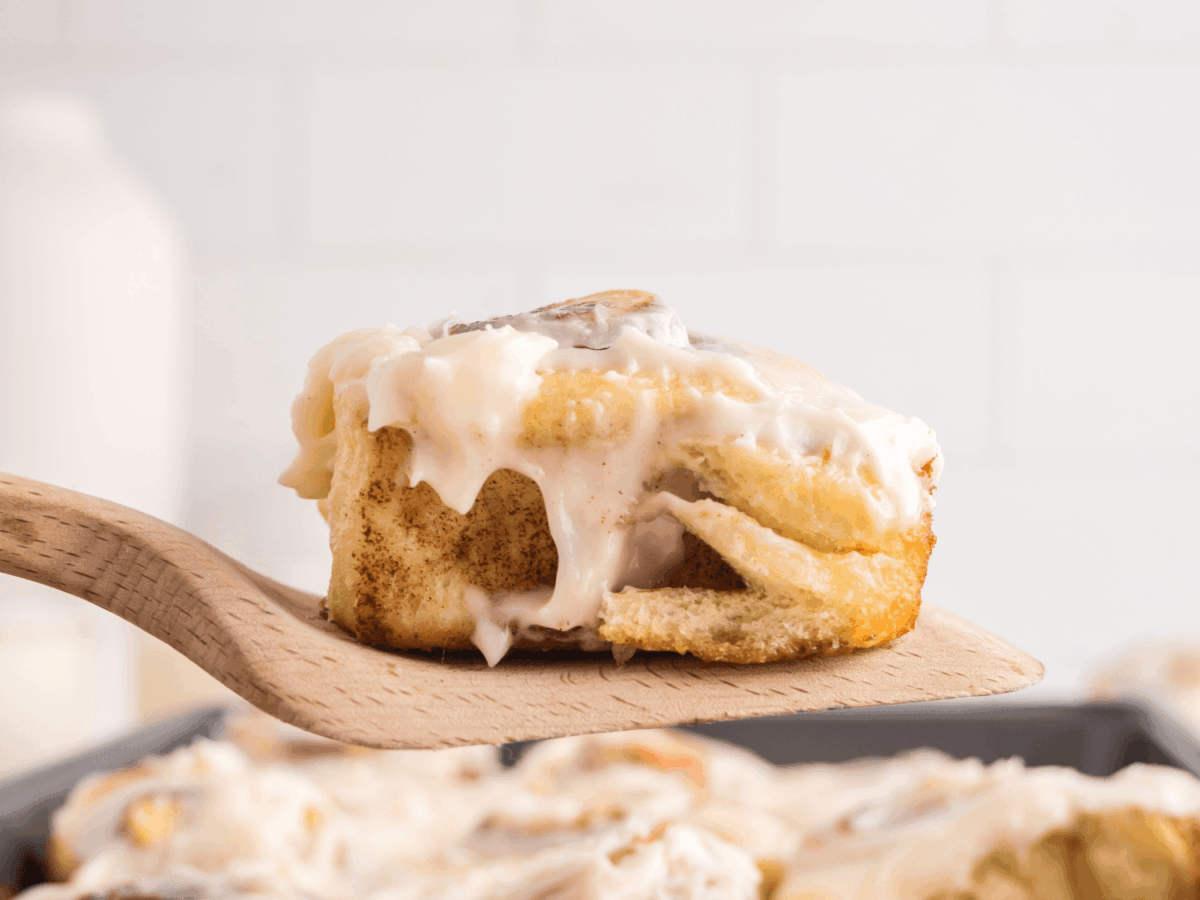 close up photo showing a cinnamon roll resting on a wooden spatula