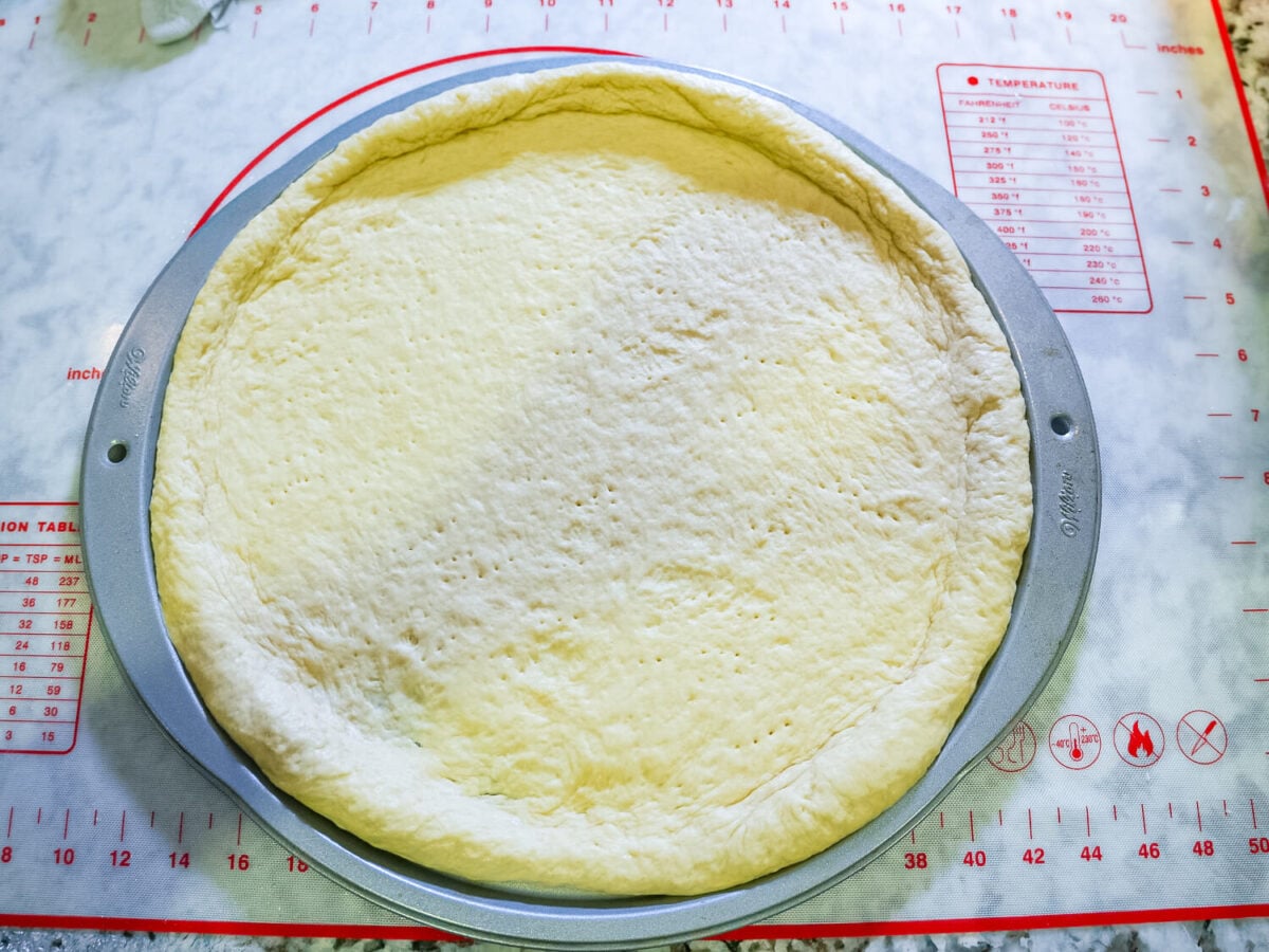overhead photo of pizza dough rolled out in a pan