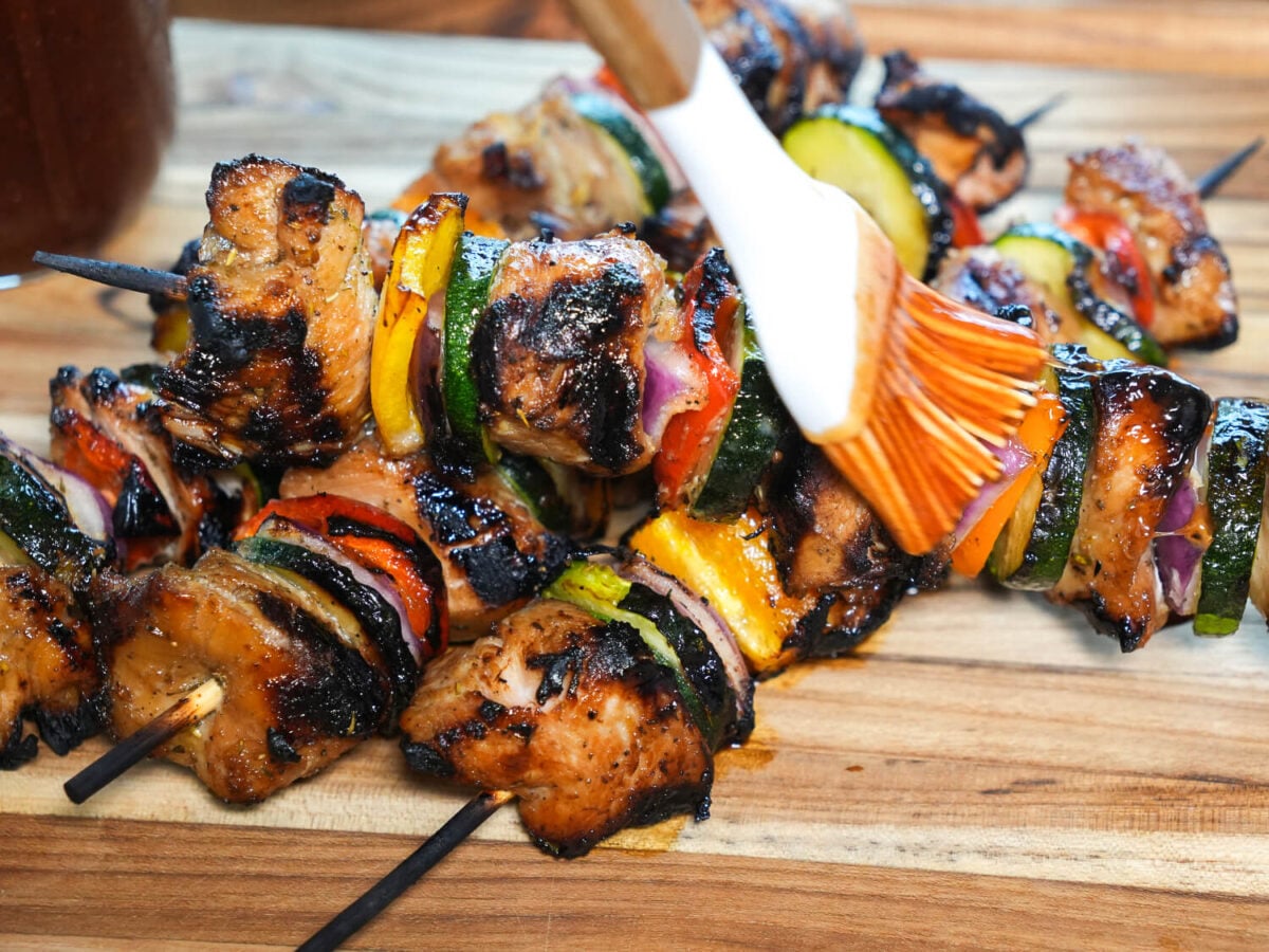 photo of grilled chicken kabobs being brushed with a bbq sauce