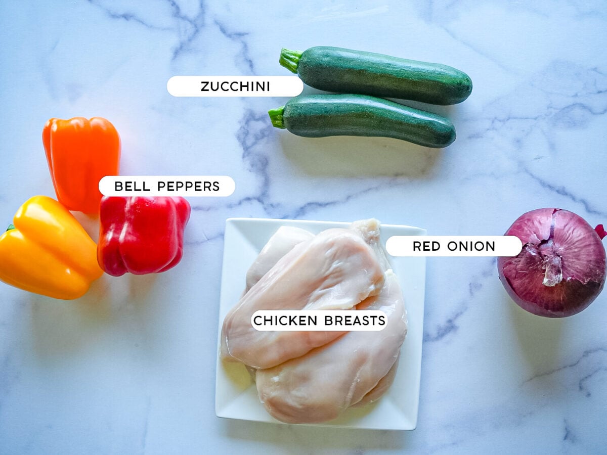 photo of ingredients needed to make chicken kabobs such as chicken, zucchini, peppers and red onion