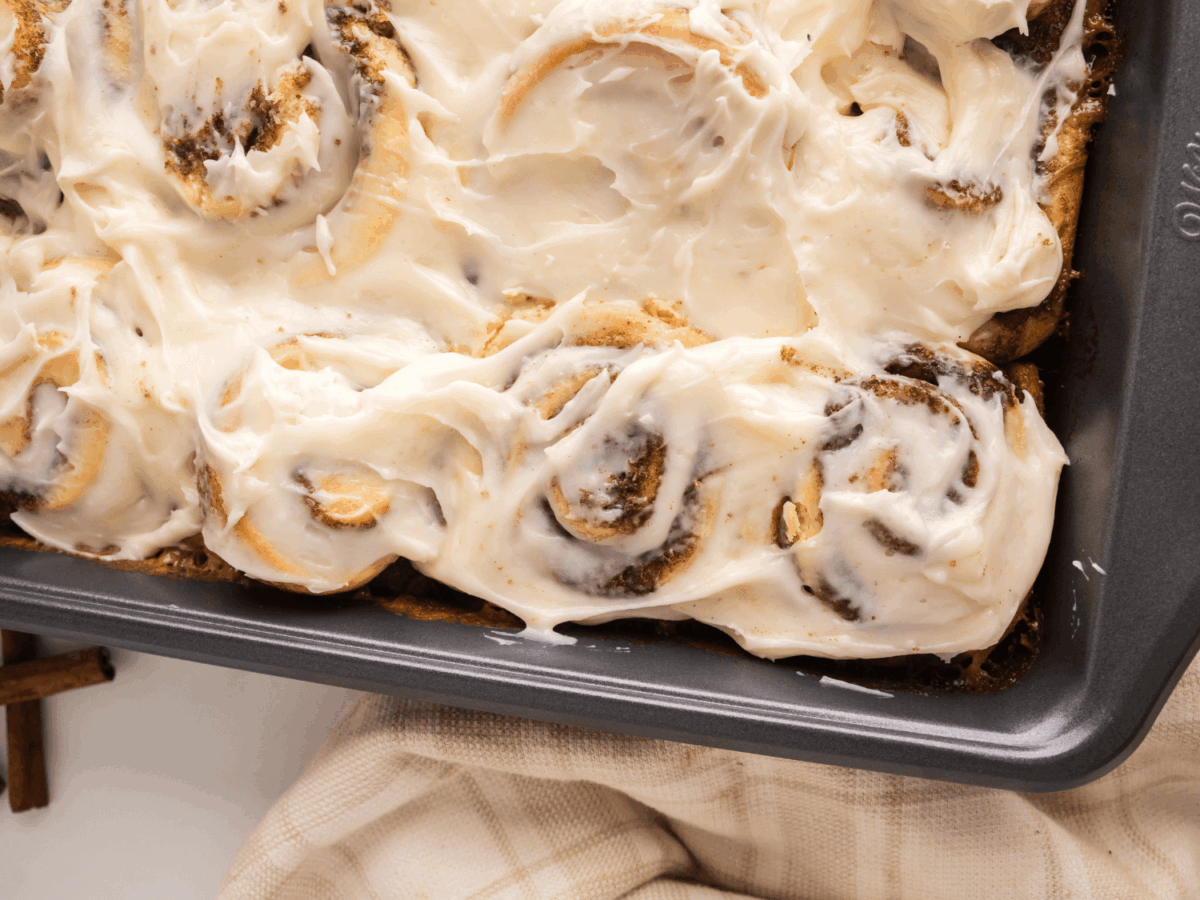 side view of cinnamon rolls with icing in the baking pan