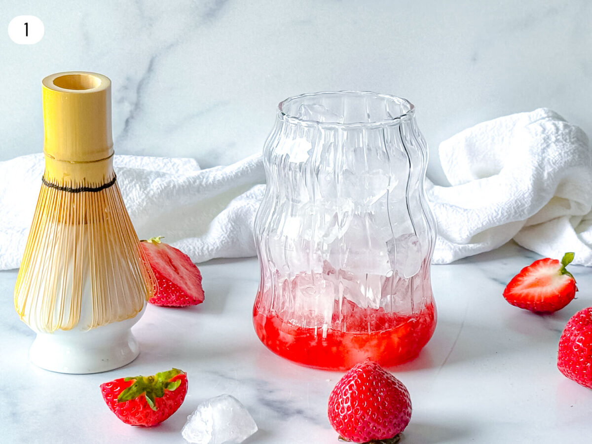 step 1 photo showing strawberry syrup and muddled strawberries in a cup