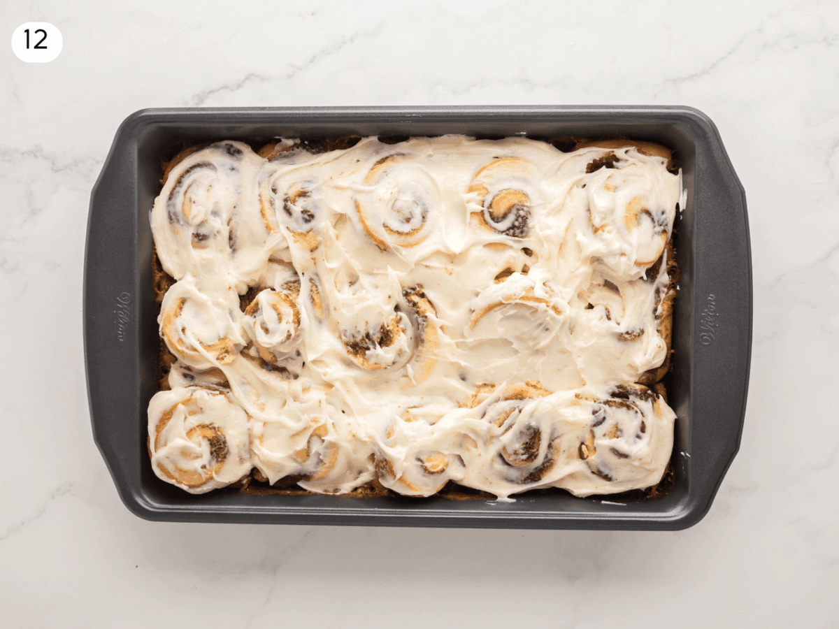 step 12 photo showing cream cheese icing thats spread on top of the cinnamon rolls before serving