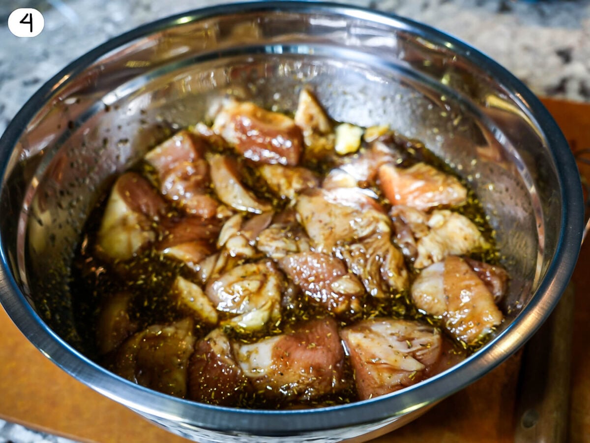 step 4 photo showing chicken sitting in marinade in a silver bowl