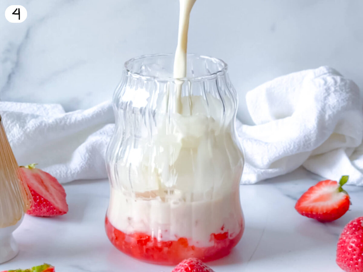 step 4 photo showing oatmilk being poured into the cup with stawberries