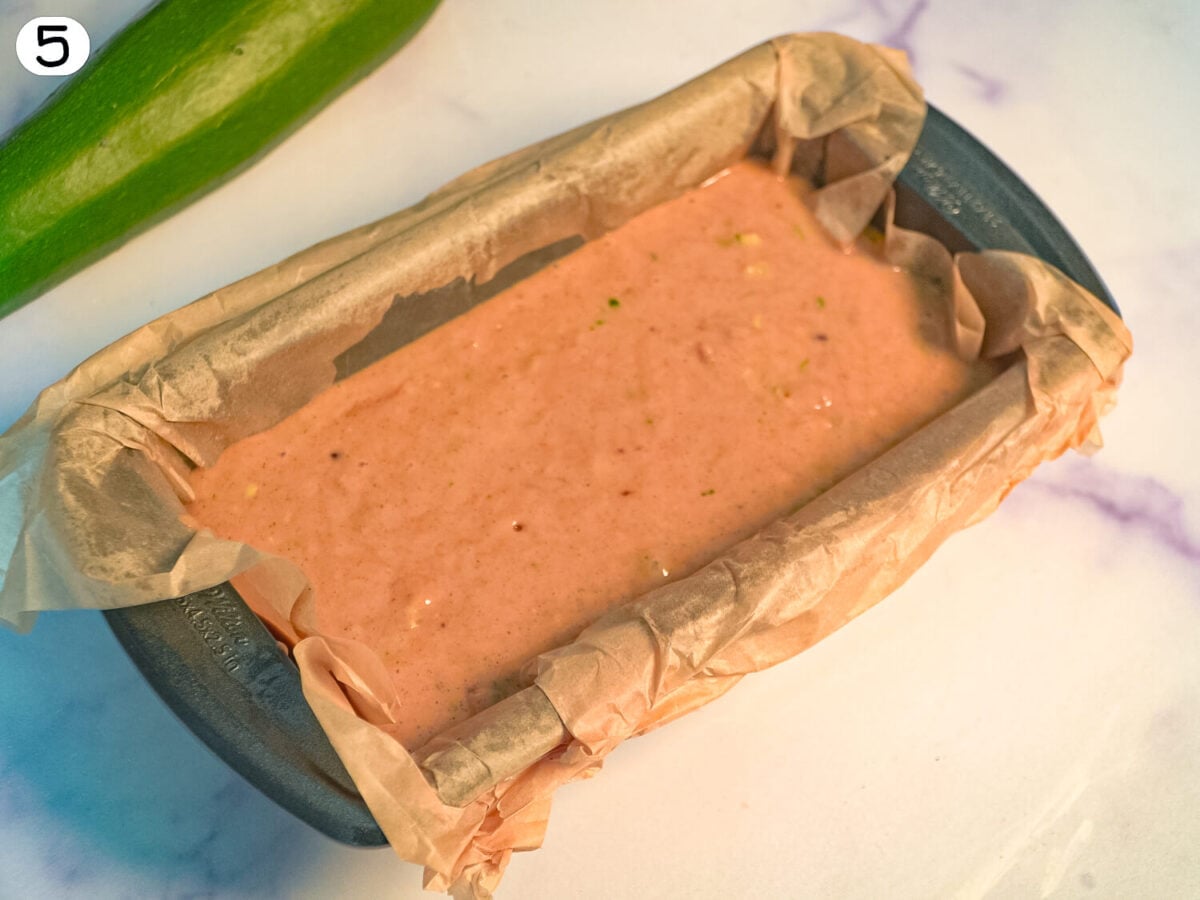 step 5 photo showing Zucchini Bread batter in a 9x5 baking pan lined with parchment paper