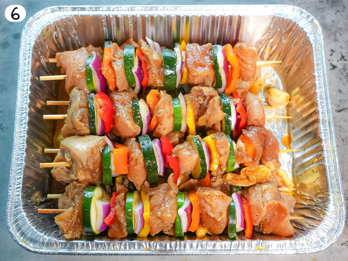 step 6 photo showing chicken and vegetable kabobs in a silver pan