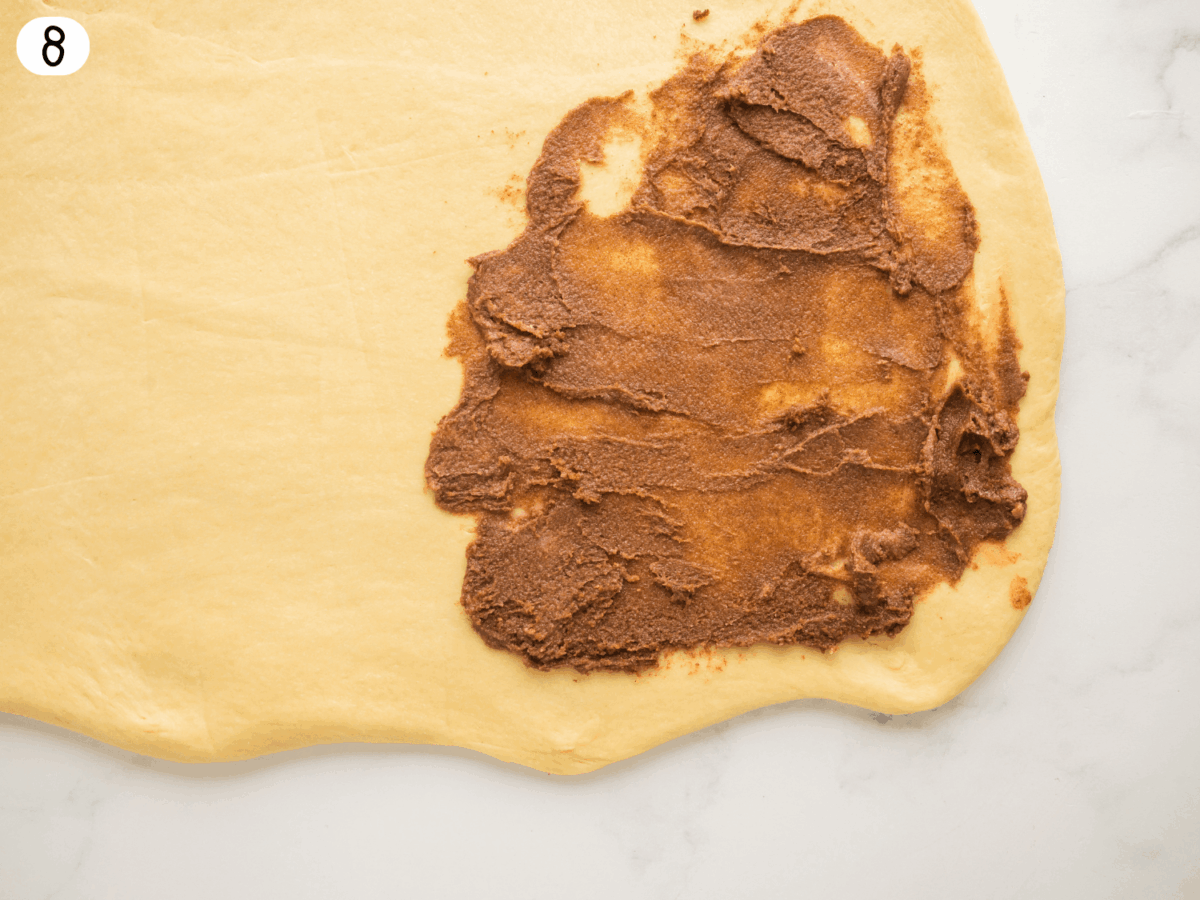 step 8 photo showing cinnamon roll filling starting to be spread onto the dough
