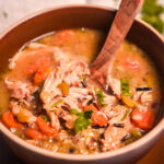 HERO photo of chicken and wild rice soup in a brown bowl with parsley on top-2