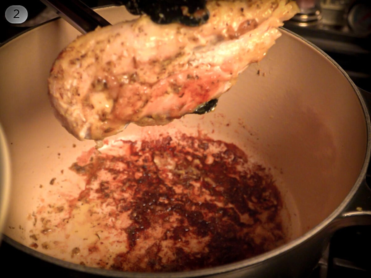 STEP 2_ Showing a seared Chicken being pulled out of the dutch oven