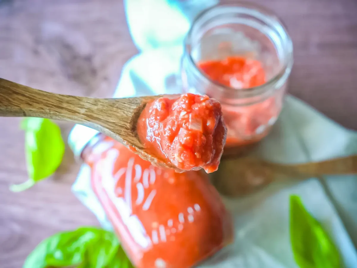 close up photo of marinara sauce on a wooden spoon