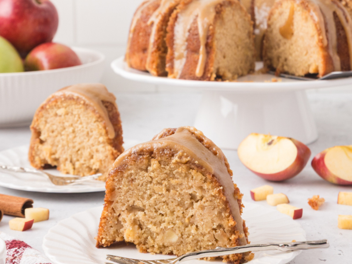 photo of 2 slices of an apple bundt cake on white plate with the apple bundt cake in the background