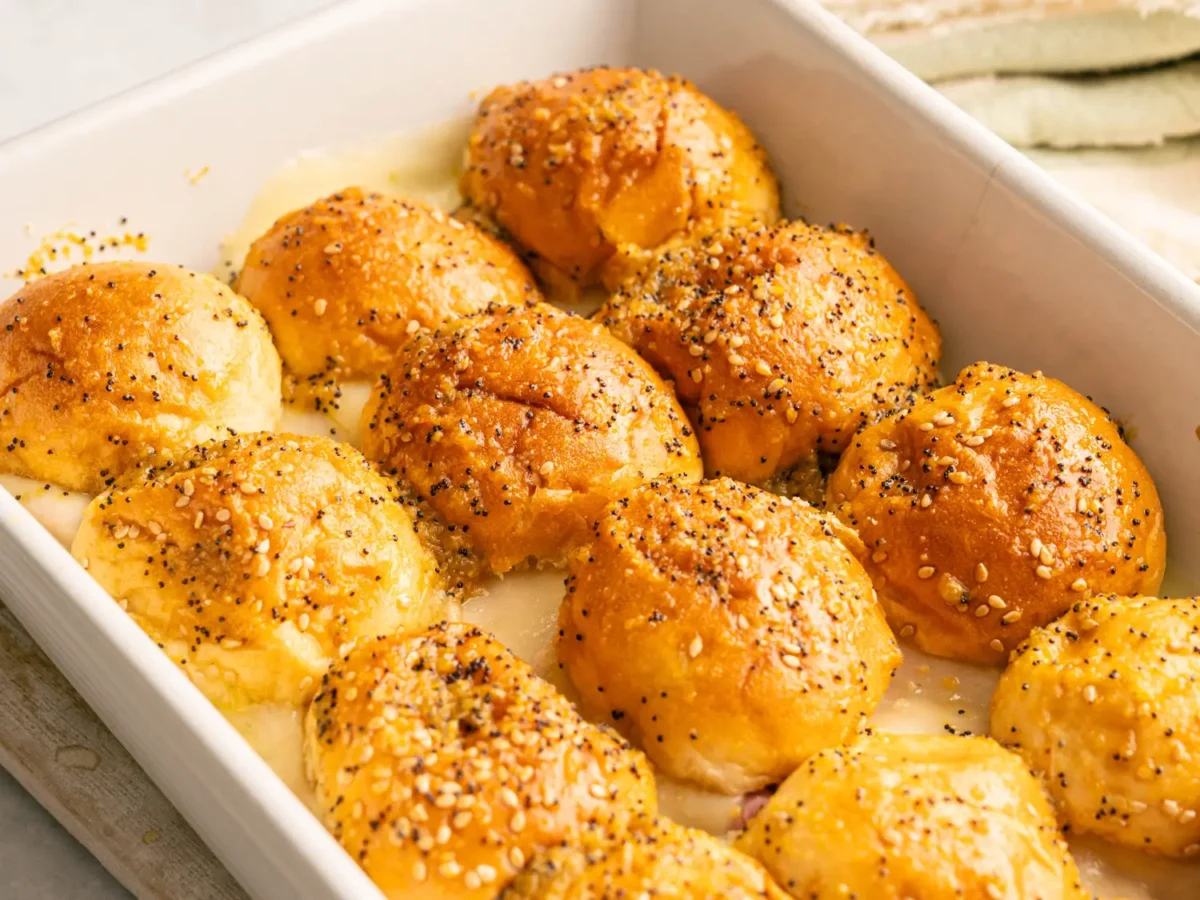 side photo of Hawaiian Bread Ham and Cheese Sliders in a white baking dish resting