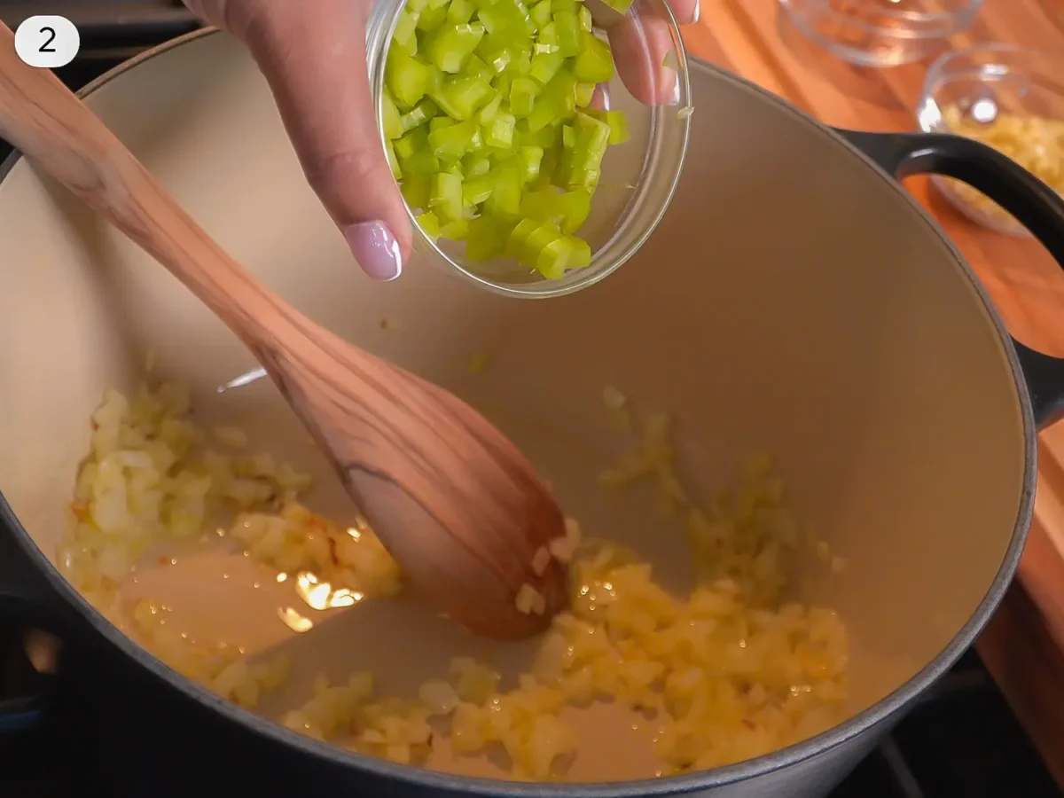 step 2 photo showing celery being added to the pot of sauteed onions