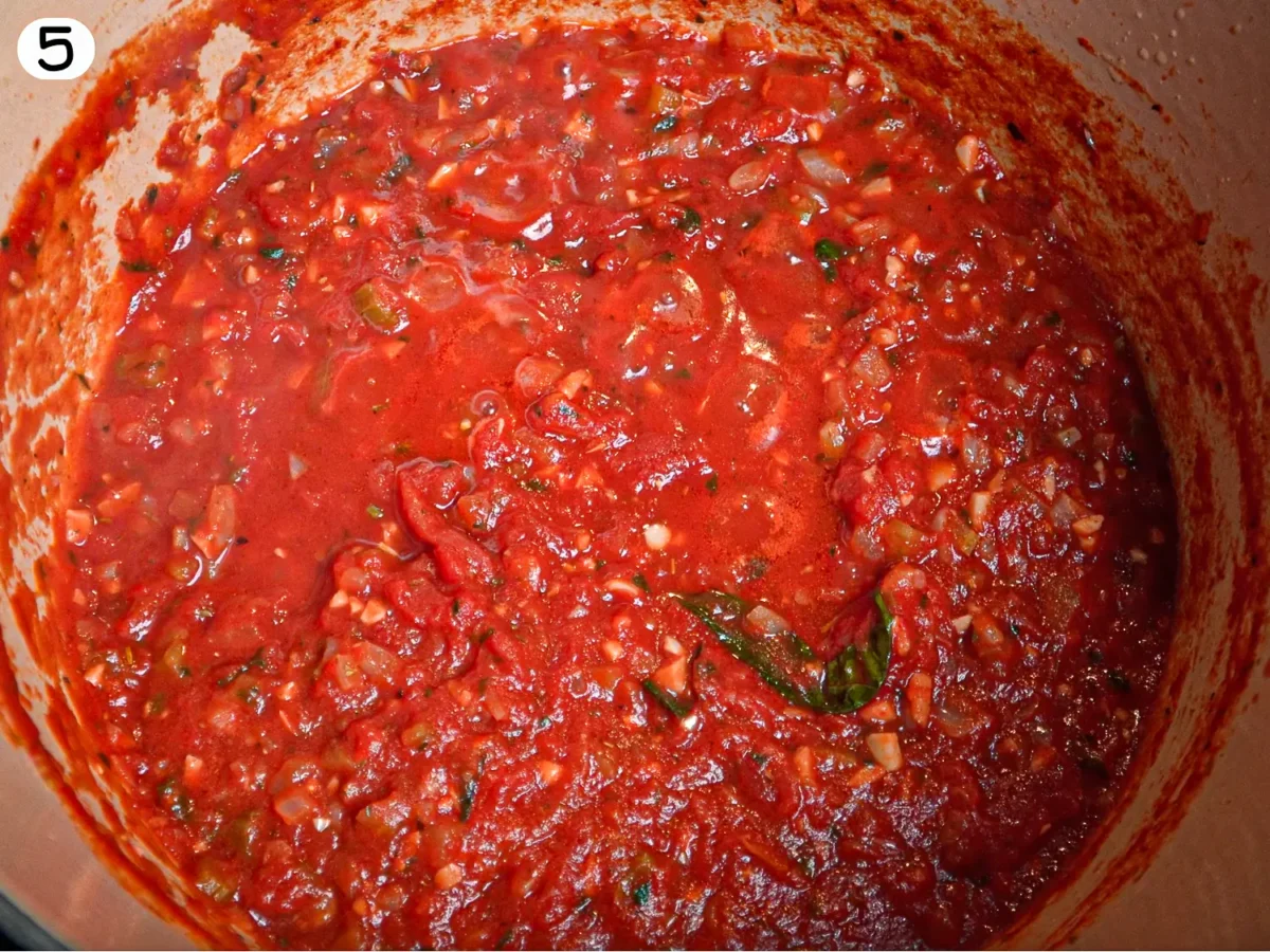 step 5 photo showing sauce simmering in the dutch oven