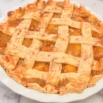 HERO homemade peach pie recipe in a white baking dish on a marble surface