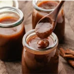 HERO photo of apple butter dripping from a wooden spoon into a glass jar