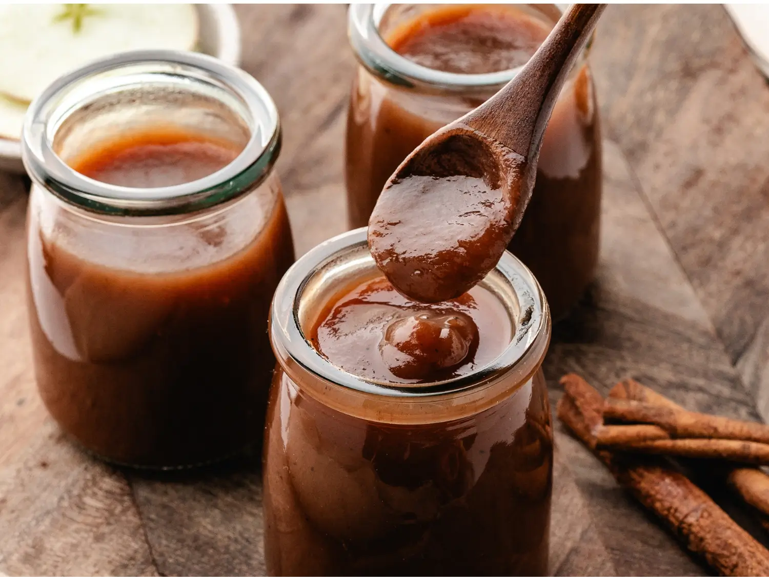 HERO photo of apple butter dripping from a wooden spoon into a glass jar
