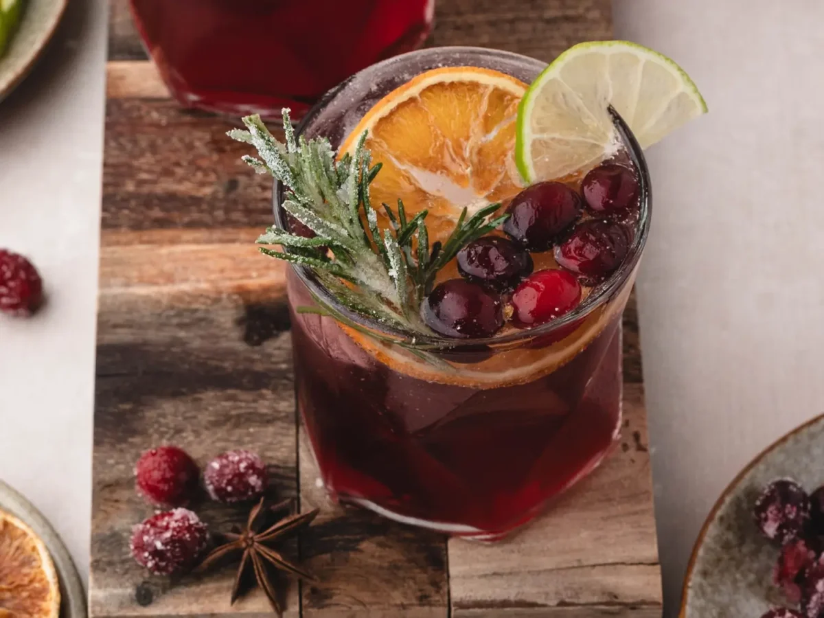 overhead photo of a cranberry mocktail that's garnished with oranges, limes, rosemary and cranberries