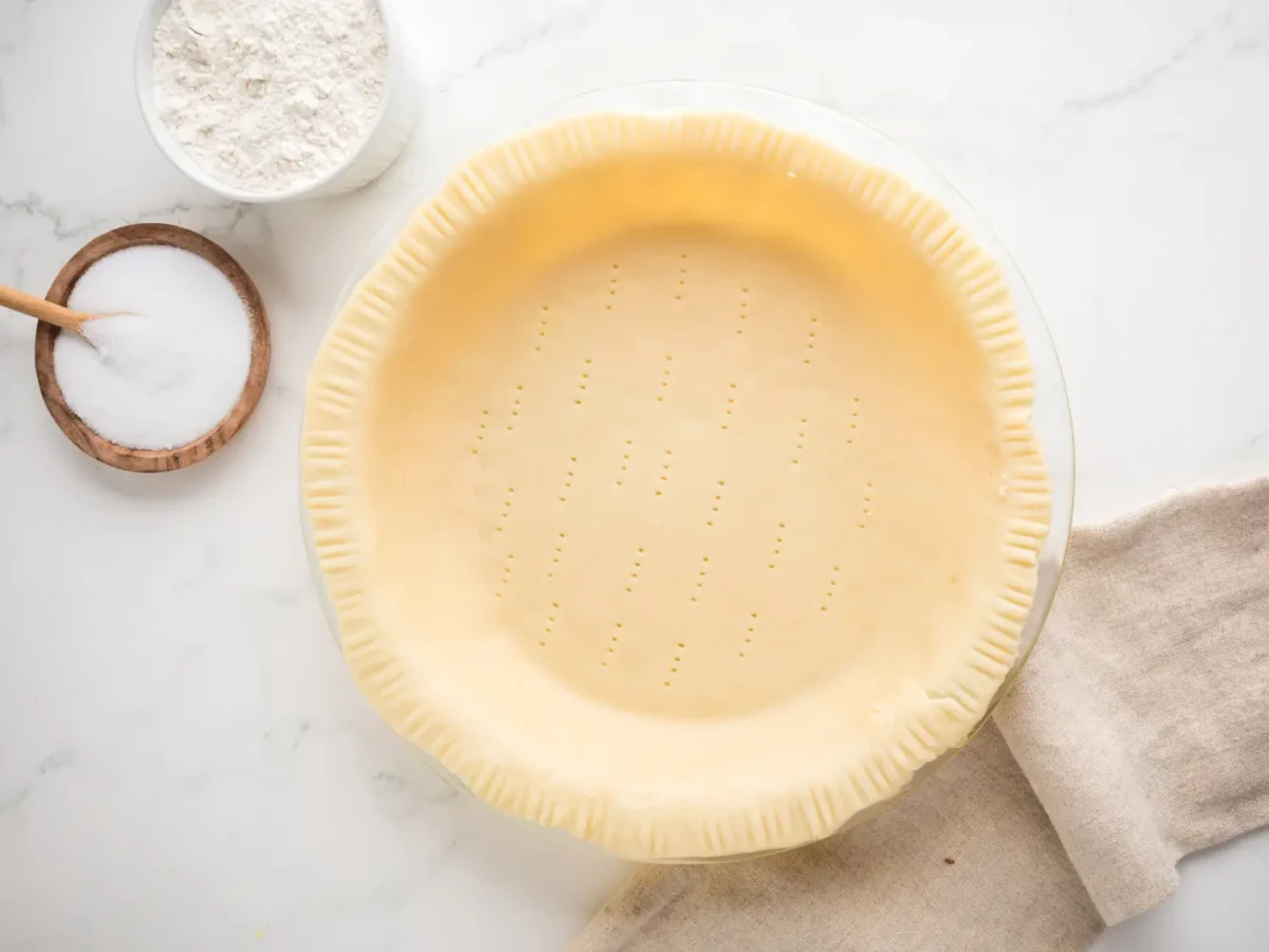 overhead photo of unbaked crisco pie crust in a pie dish next to flour and sugar ingredients