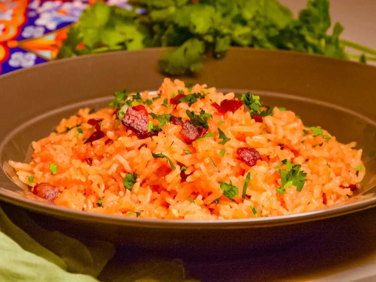 photo of Charleston Red Rice in a brown bowl with garnished bacon and cilantro