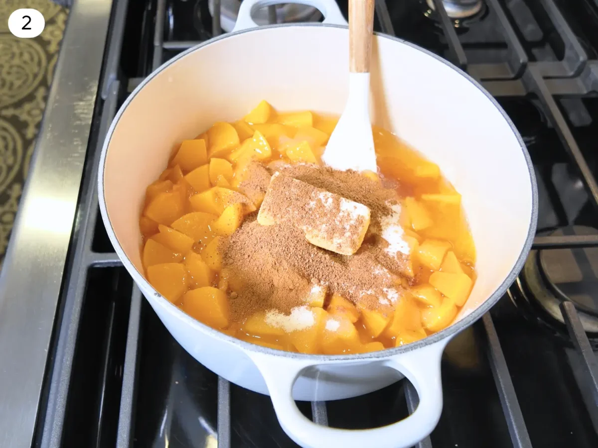step 2 photo showing butter sugar cinnamon and nutmeg added to the peaches in the sauce pan