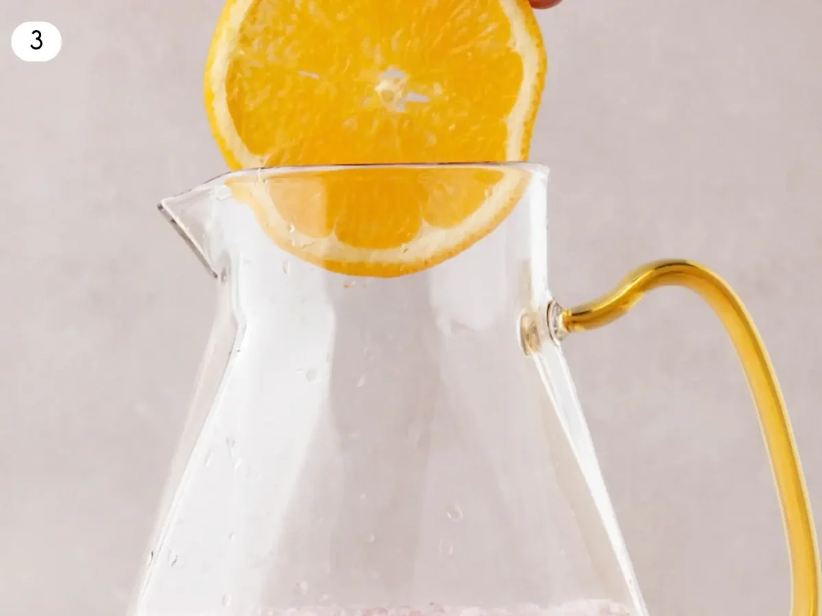 step 3 photo showing orange slices being added to a pitcher