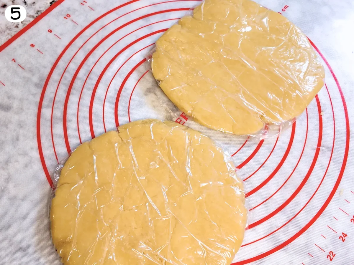 step 5 photo showing pie dough divided into two discs covered in plastic wrap